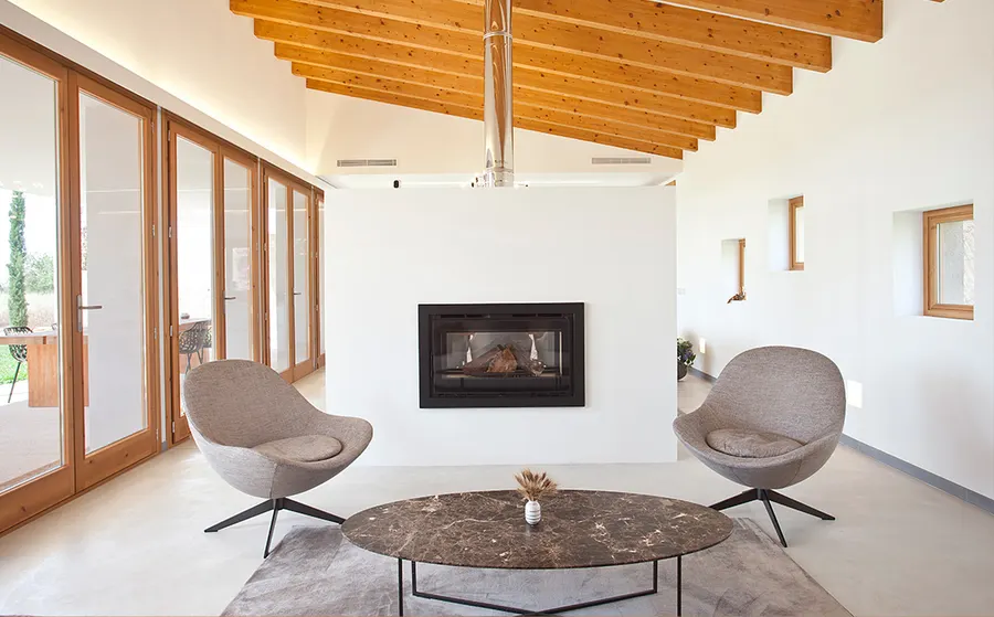 Living room with fireplace and wooden ceiling in a new Mallorcan house
